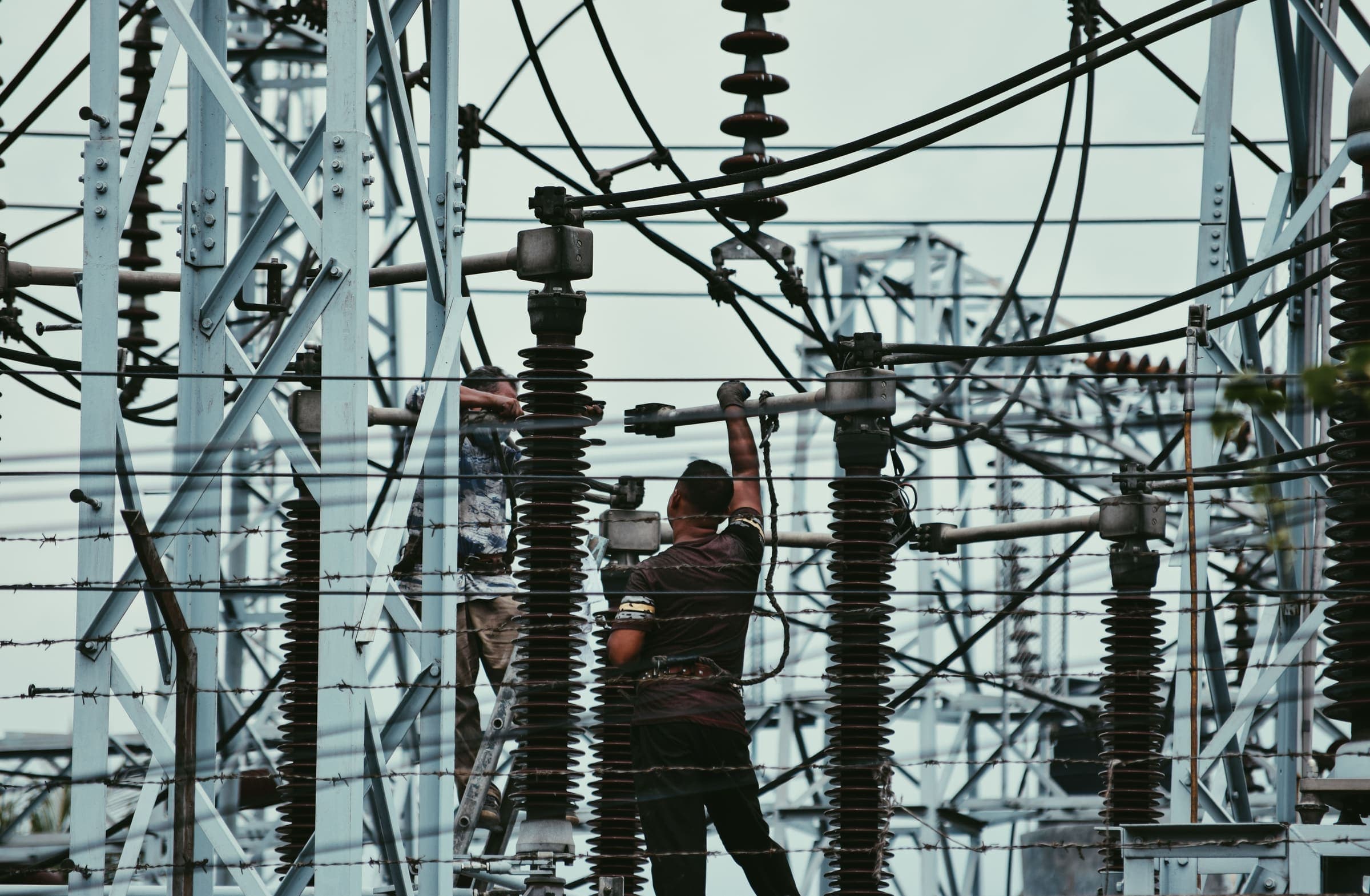 Technicians servicing high-voltage equipment at a substation
