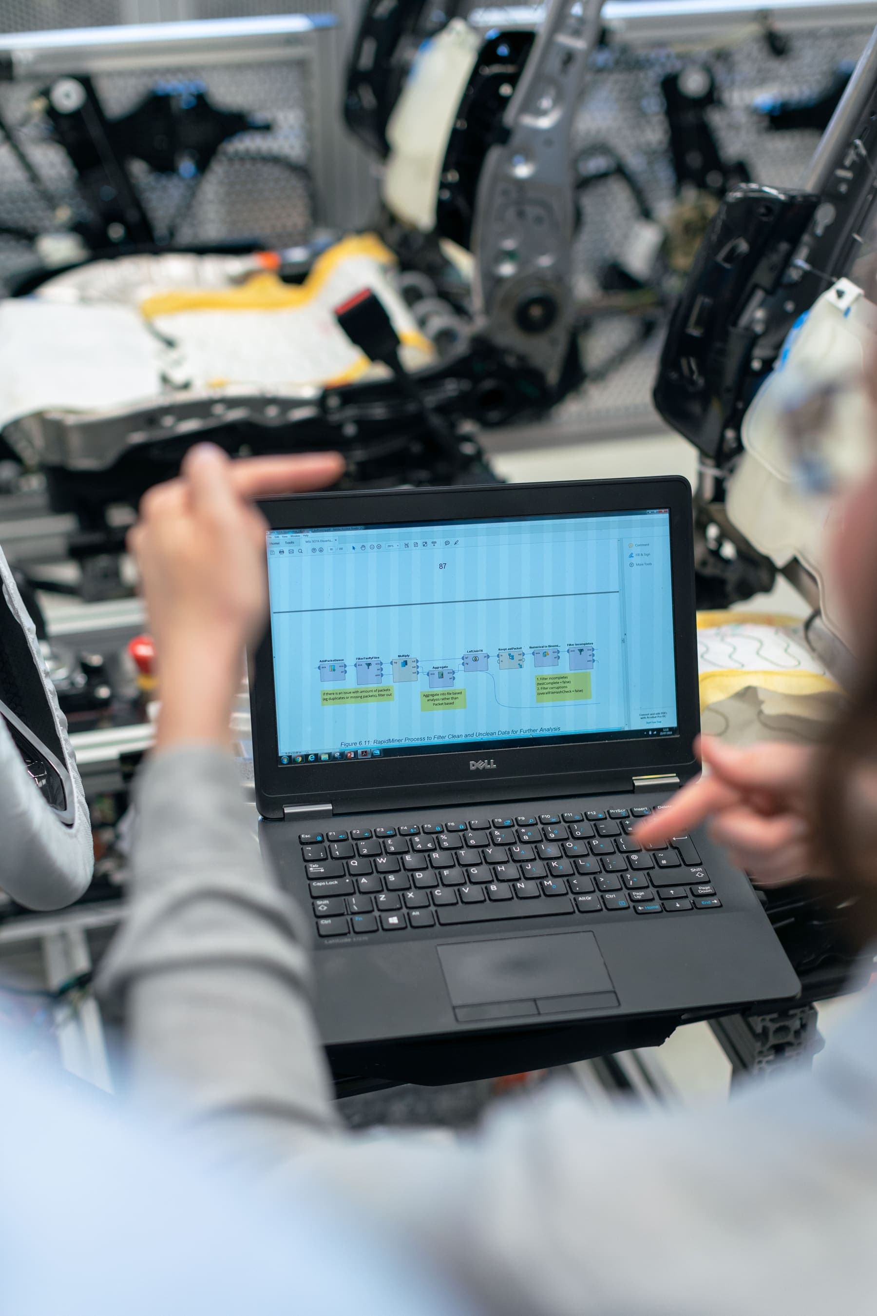 Engineers reviewing a data pipeline on a laptop beside test rigs
